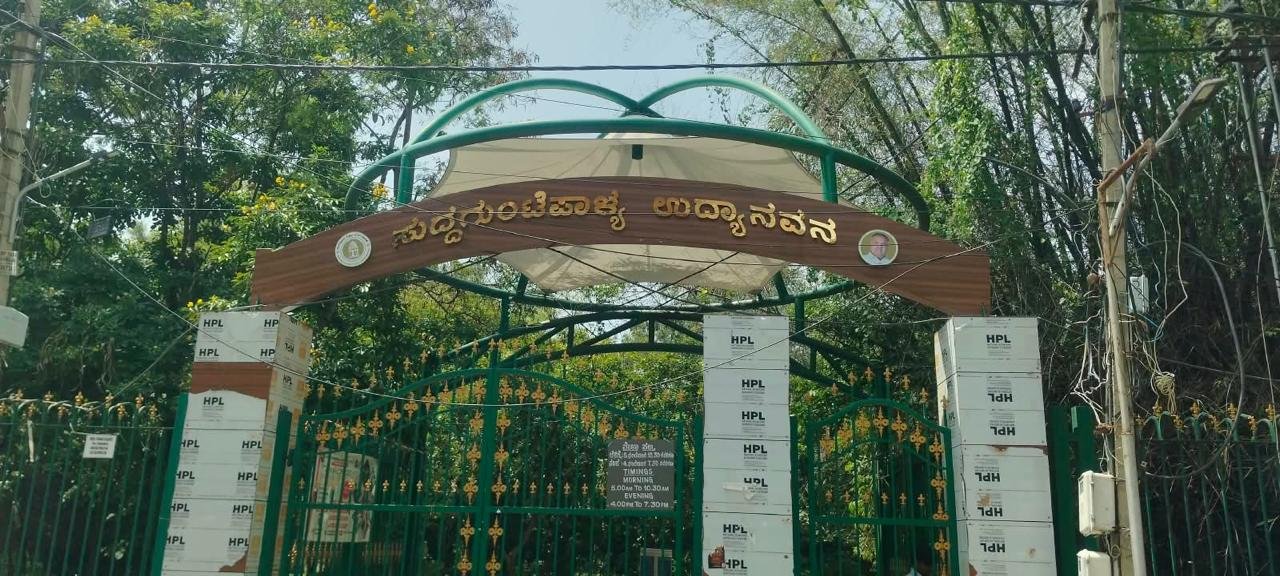ಹಸಿರು ಗೇಟ್ ಮತ್ತು ಮರಗಳಿಂದ ಆವೃತ ಉದ್ಯಾನವನದ ಪ್ರವೇಶದ್ವಾರ.