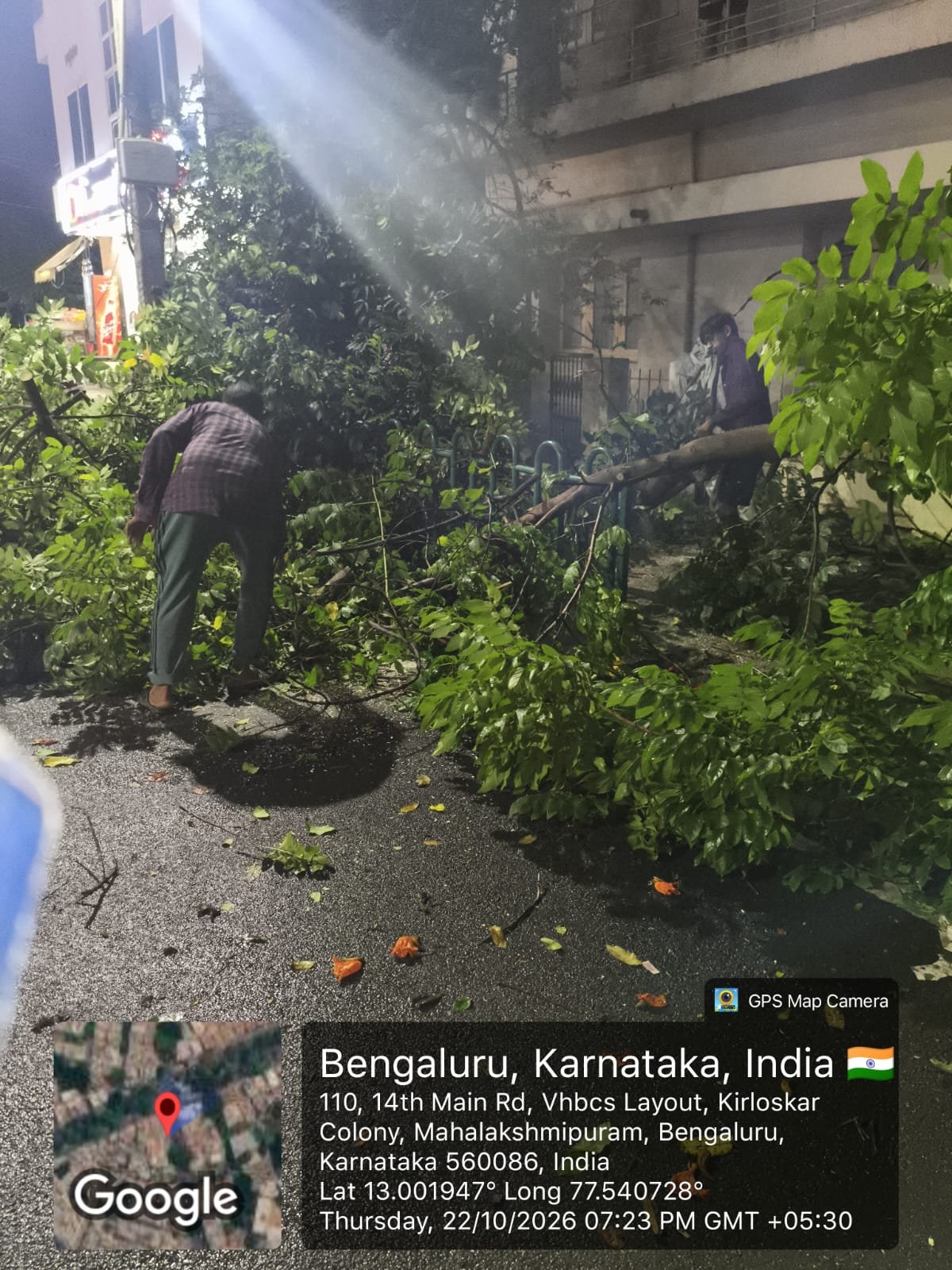 ಬೆಂಗಳೂರಿನ ಮಹಾಲಕ್ಷ್ಮೀಪುರದಲ್ಲಿ ಒದ್ದೆಯಾದ ರಸ್ತೆಬದಿಯಿಂದ ಮರದ ಕೊಂಬೆಗಳನ್ನು ತೆರವುಗೊಳಿಸುತ್ತಿರುವ ಜನರು; ಅಕ್ಟೋಬರ್ 22, 2026ರ ಚಿತ್ರ